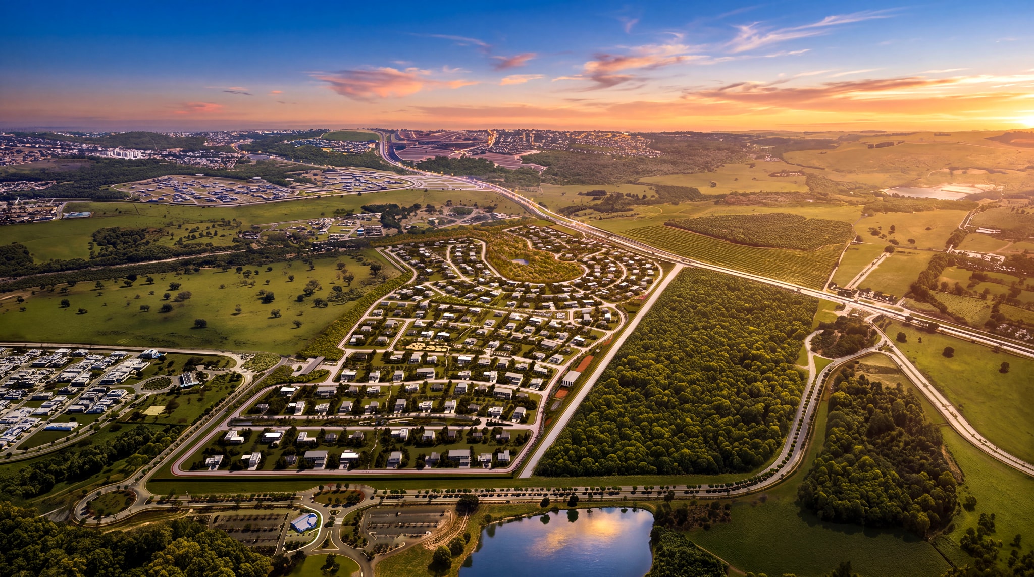 Vista aérea do loteamento ao entardecer, com o eixo rodoviário ao fundo